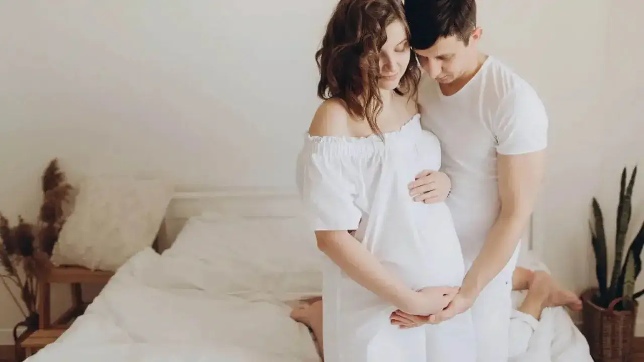 Un couple s'enlacent tendrement, la femme enceinte caresse son ventre. Ils semblent surmonter un blocage psychologique grossesse, trouvant du r&eacute;confort l'un dans l'autre.