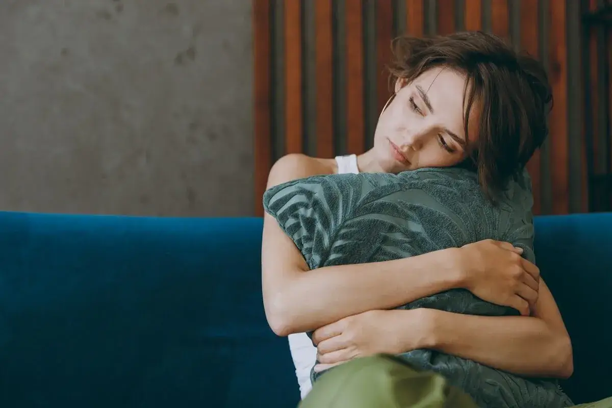Une femme &eacute;treint un coussin, le visage appuy&eacute; dessus, le regard perdu. Elle cherche du r&eacute;confort, une aide pour savoir comment r&eacute;agir quand un homme vous quitte.