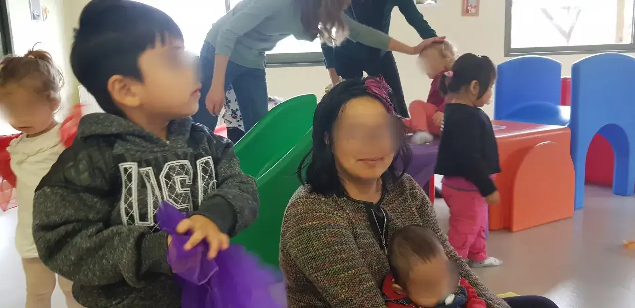 Une m&egrave;re au foyer surveille ses enfants jouant dans une aire de jeux int&eacute;rieure color&eacute;e.