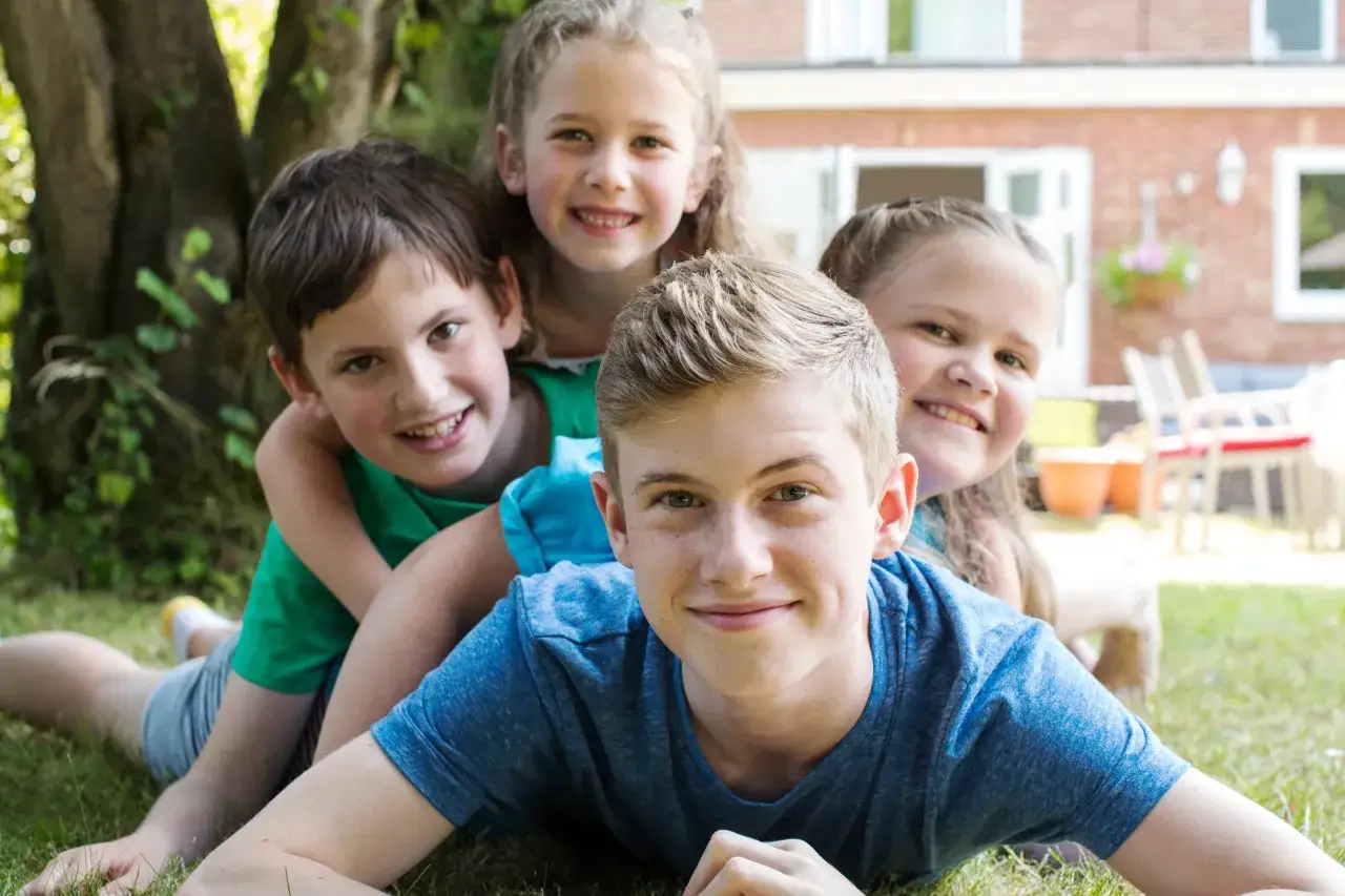 Le sourire de l'ain&eacute; de la famille, entour&eacute; de ses fr&egrave;res et s&oelig;urs, rayonne de joie dans le jardin.