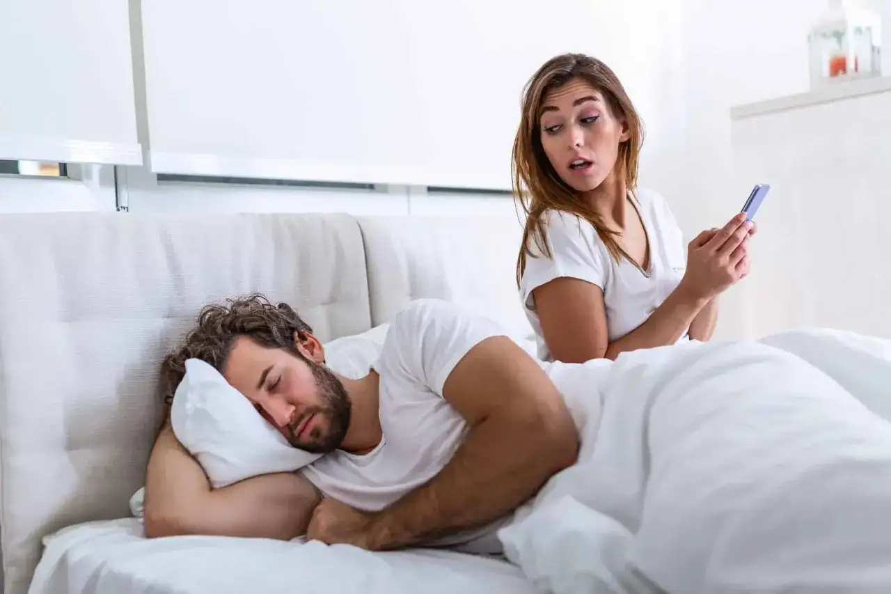 Elle regarde son téléphone avec inquiétude pendant que son partenaire dort. Mon ex revient, mais je n'ai plus confiance.