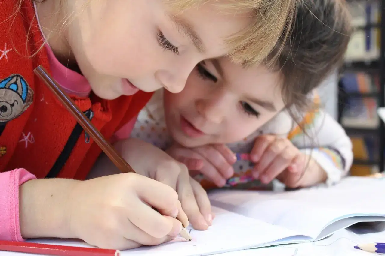 Deux enfants concentrés sur un exercice, peut-être un iq test for kids. L'un écrit, l'autre observe.