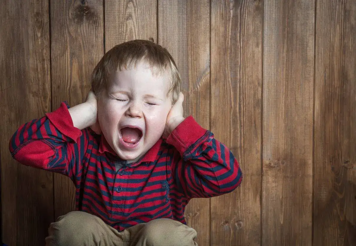 Petit gar&ccedil;on de 5 ans, yeux ferm&eacute;s, criant fort et se bouchant les oreilles, en pleine crise de col&egrave;re incontr&ocirc;lable.