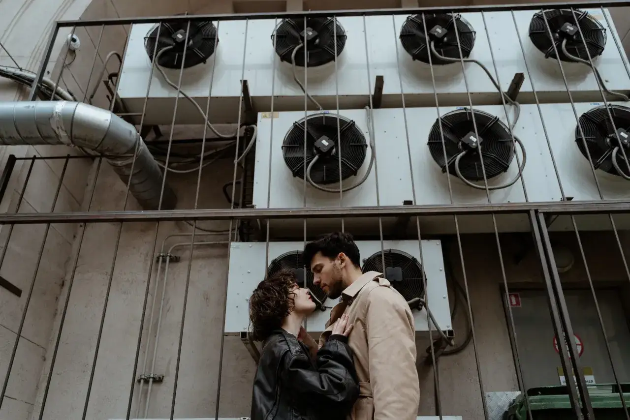 Un couple s'embrasse devant des unit&eacute;s de climatisation. Mon ex m'aime encore, mais il a une copine.