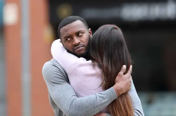 Un homme étreint une femme, mais son regard trahit une préoccupation. Comment savoir s'il pense à moi ?