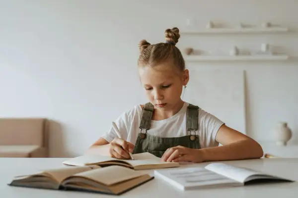 Jeune fille concentrée sur son cahier, peut-être en pleine préparation d'un test HPI WISC.